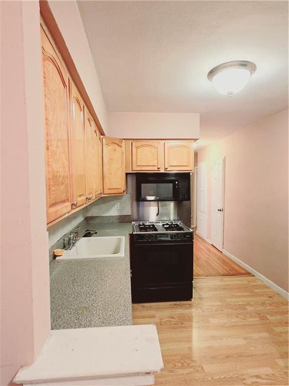 kitchen featuring light brown cabinetry, sink, light hardwood / wood-style flooring, and black appliances