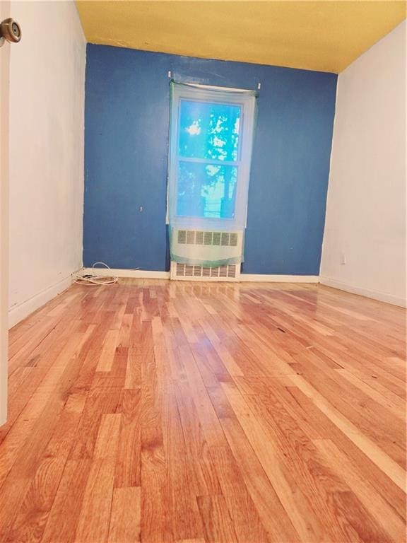 empty room with light hardwood / wood-style floors and radiator heating unit