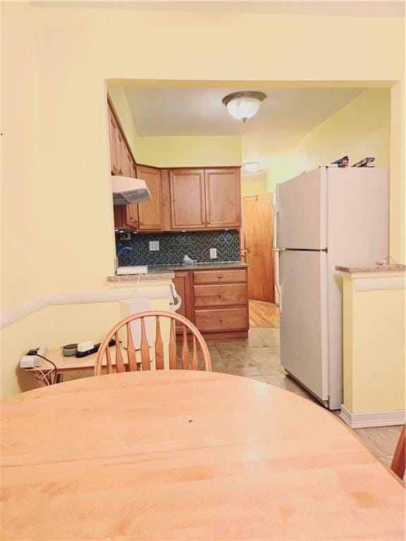 kitchen featuring decorative backsplash, white fridge, and light wood-type flooring