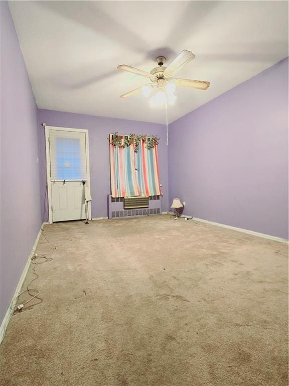 carpeted spare room featuring ceiling fan and radiator heating unit