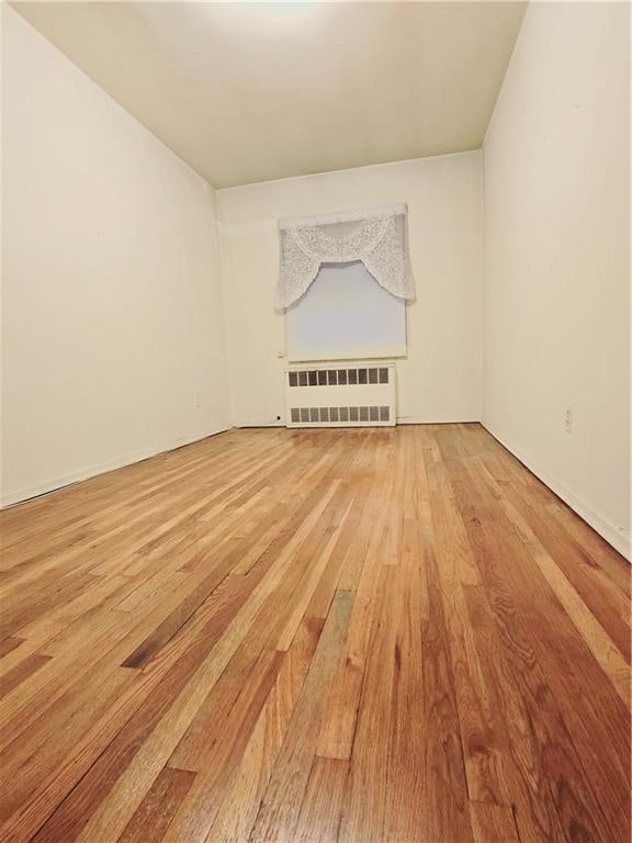 unfurnished living room with radiator heating unit and light wood-type flooring