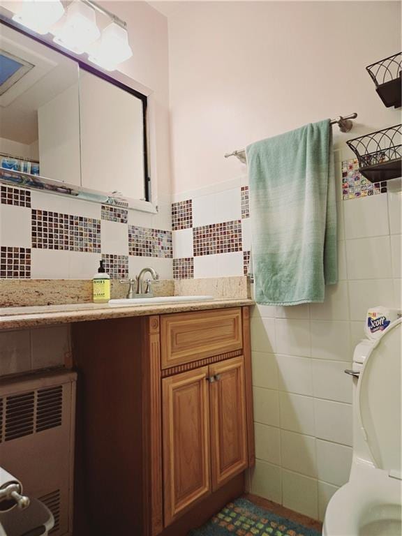 bathroom with vanity, tile walls, and toilet