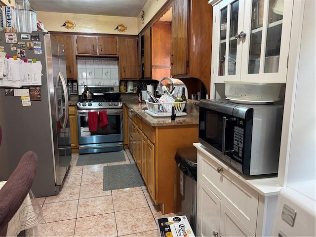 kitchen with tasteful backsplash, light tile patterned floors, and stainless steel appliances