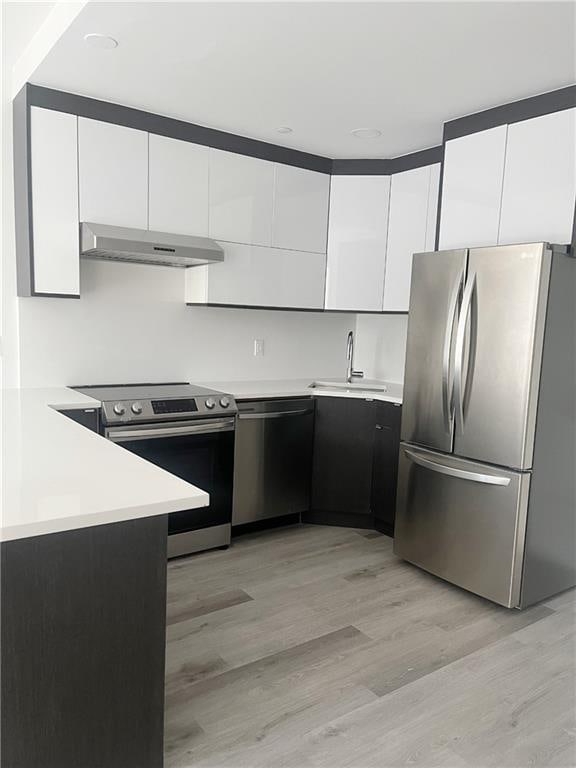 kitchen with white cabinets, stainless steel appliances, light hardwood / wood-style flooring, and sink