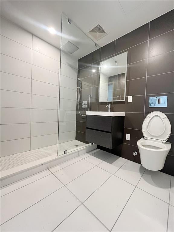 bathroom with vanity, tile patterned flooring, toilet, tile walls, and walk in shower