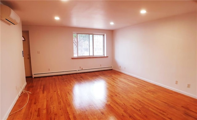 spare room featuring light wood-type flooring, a baseboard radiator, and a wall mounted AC