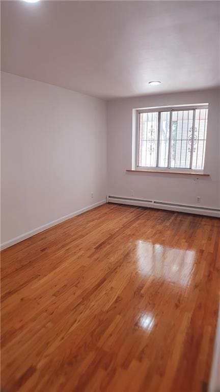 empty room featuring plenty of natural light, light hardwood / wood-style floors, and a baseboard radiator