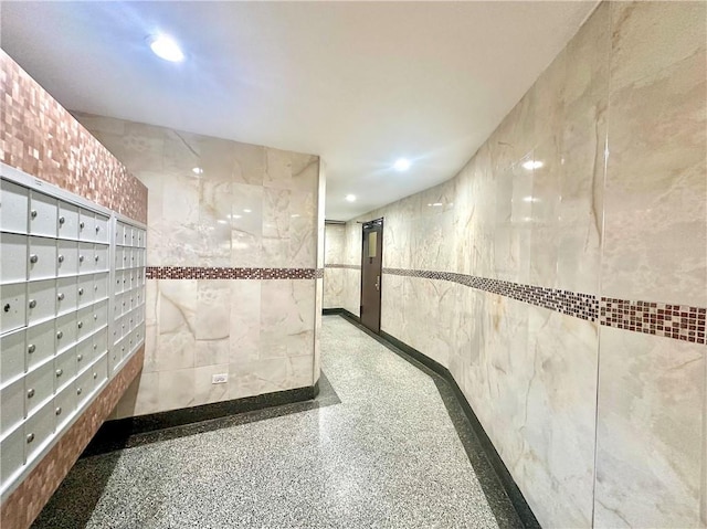 hallway with tile walls and a mail area