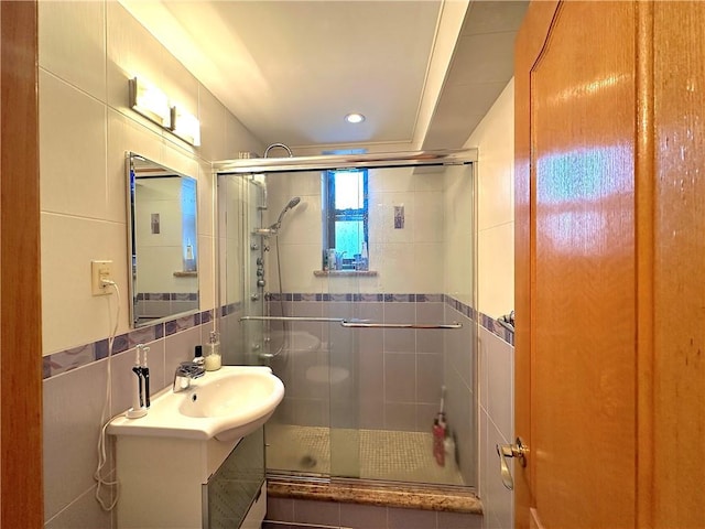 bathroom featuring vanity, a shower with shower door, and tile walls