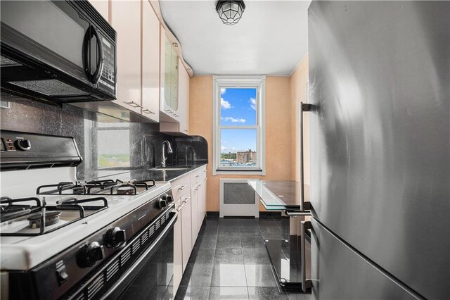 kitchen with stainless steel fridge, range with gas cooktop, white cabinetry, and sink