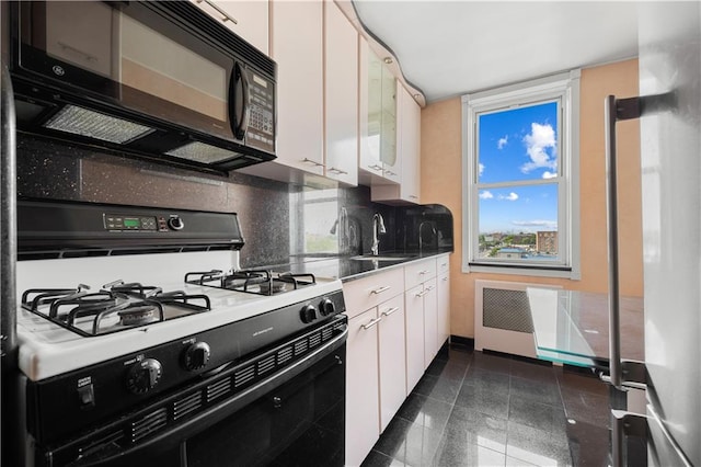 kitchen featuring white cabinets, decorative backsplash, gas stove, and sink