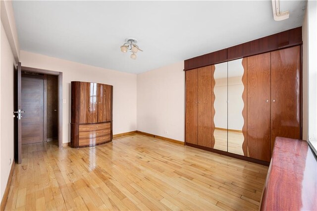 unfurnished bedroom featuring light hardwood / wood-style floors and a closet