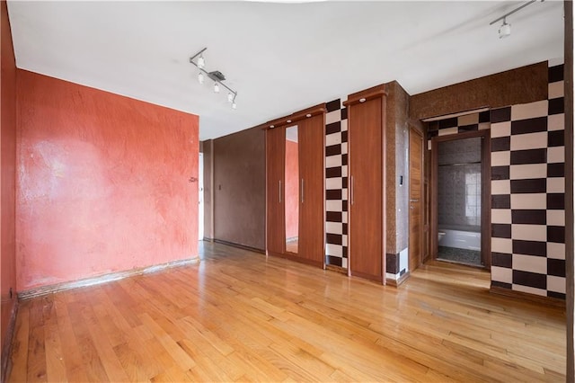 unfurnished room with track lighting and light wood-type flooring