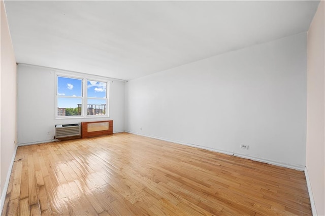 unfurnished room featuring light wood-type flooring and a wall mounted AC