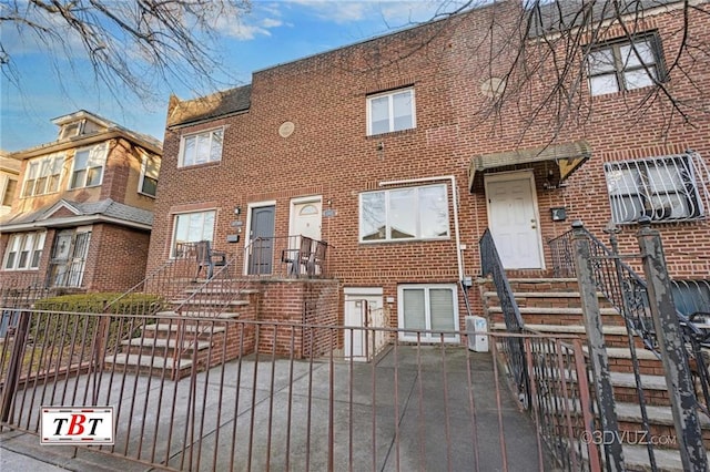 view of property featuring brick siding and fence