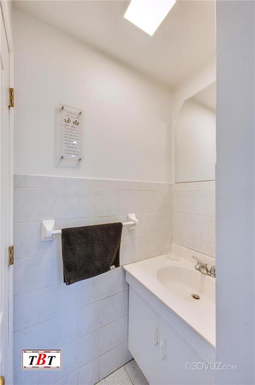 bathroom featuring tile patterned flooring, vanity, and tile walls