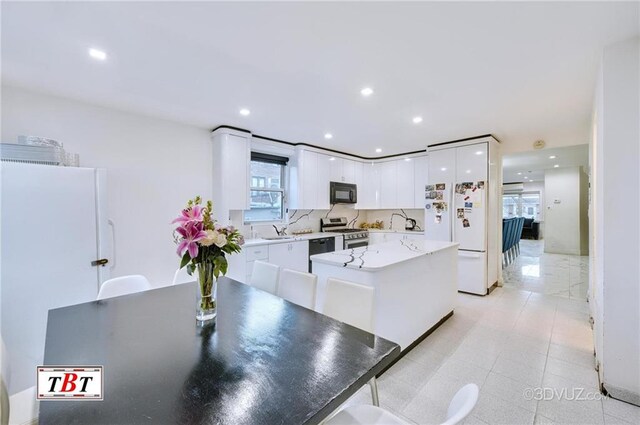 kitchen featuring a kitchen island, white cabinetry, dishwashing machine, white fridge, and stainless steel range