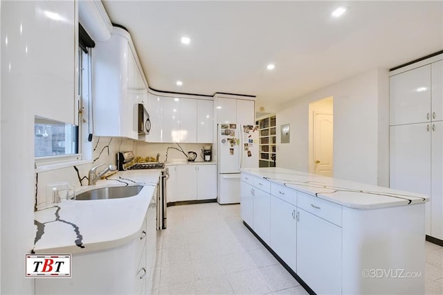 kitchen featuring sink, white cabinets, decorative backsplash, a center island, and white appliances