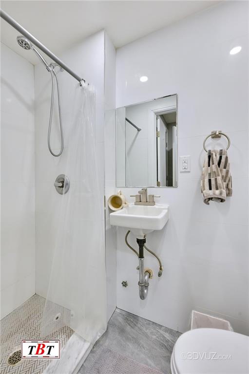 bathroom featuring toilet, sink, and a tile shower