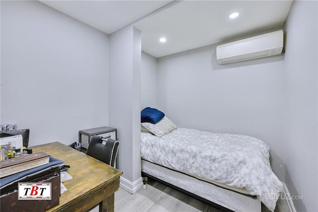 bedroom with a wall mounted air conditioner and light hardwood / wood-style flooring