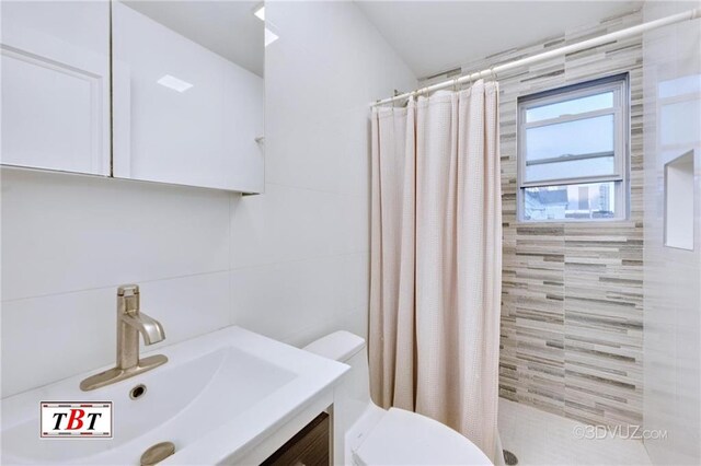 bathroom with a shower with curtain, vanity, toilet, and tile walls