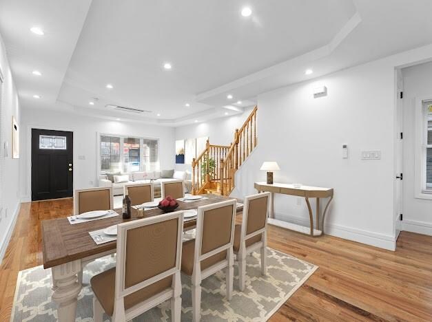 dining area with a raised ceiling and light wood-type flooring