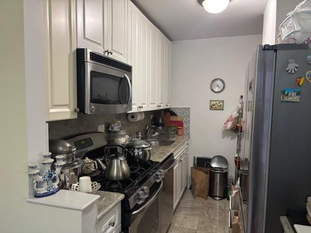 kitchen with light stone counters, sink, white cabinetry, and appliances with stainless steel finishes