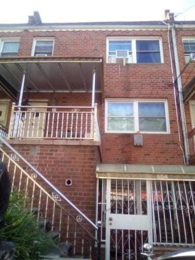 back of house featuring a balcony and brick siding