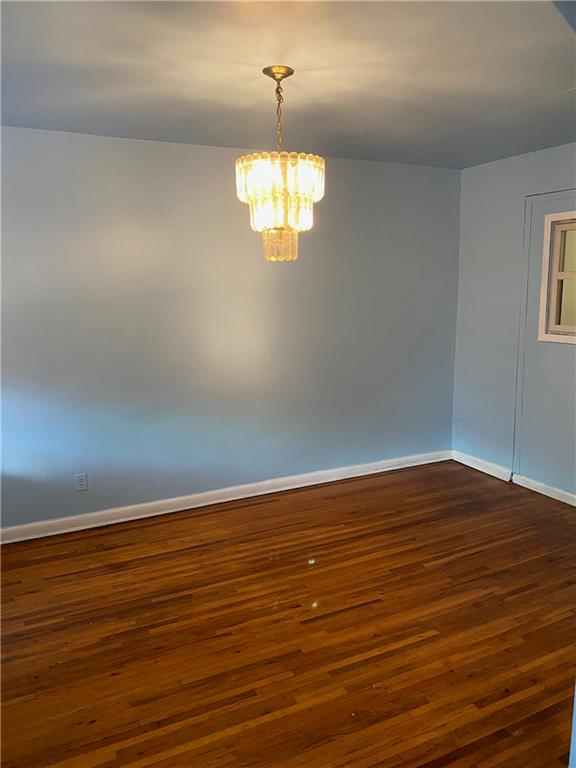 unfurnished room featuring dark hardwood / wood-style floors and a notable chandelier