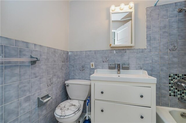 bathroom with vanity, toilet, and tile walls