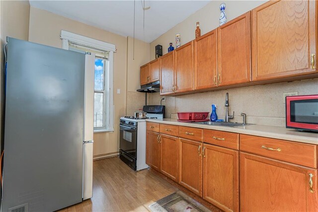 kitchen with a wealth of natural light, black gas stove, sink, and stainless steel refrigerator