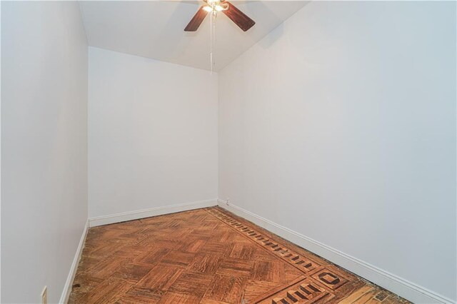 empty room featuring ceiling fan, dark parquet flooring, and vaulted ceiling