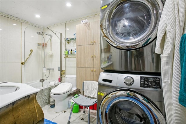 interior space with sink, tile patterned floors, toilet, stacked washer and clothes dryer, and tiled shower / bath