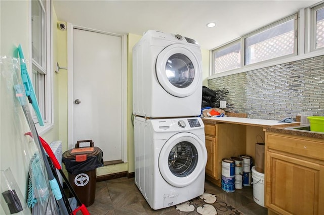 washroom with stacked washer / dryer, dark parquet floors, and cabinets