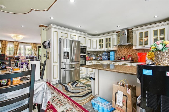 kitchen with backsplash, white cabinets, wall chimney exhaust hood, stainless steel fridge, and dark stone countertops