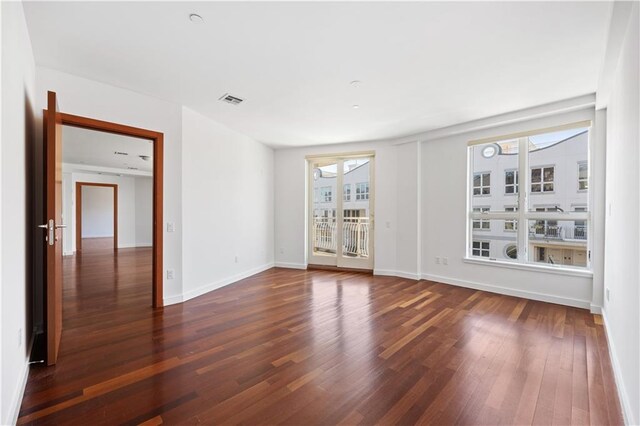 unfurnished room featuring a wealth of natural light and dark hardwood / wood-style floors