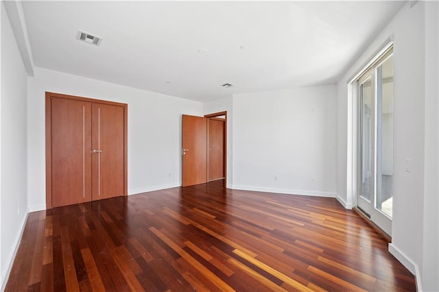 unfurnished bedroom with dark hardwood / wood-style floors and a closet