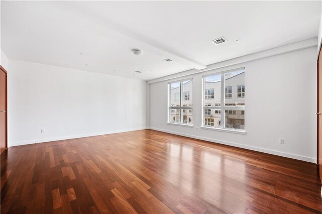 spare room with beam ceiling and dark wood-type flooring