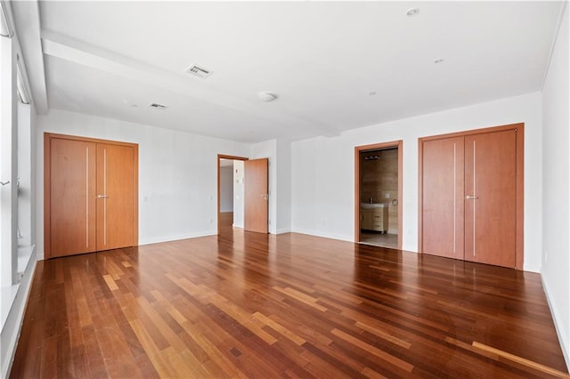 unfurnished bedroom featuring hardwood / wood-style floors and connected bathroom