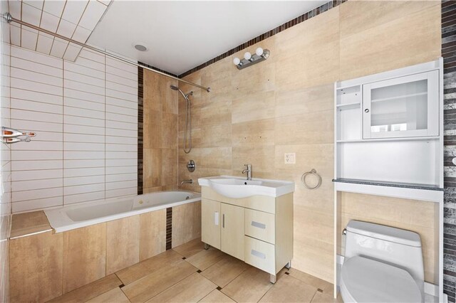 full bathroom featuring tile patterned flooring, vanity, tile walls, and tiled shower / bath