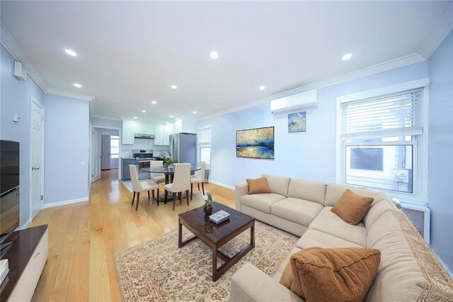 living room with light wood-type flooring, crown molding, and a wall unit AC