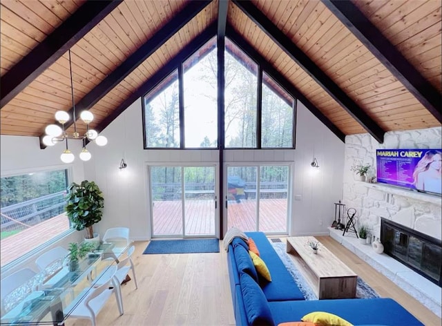 living room featuring a fireplace, beamed ceiling, light hardwood / wood-style flooring, wood ceiling, and a chandelier