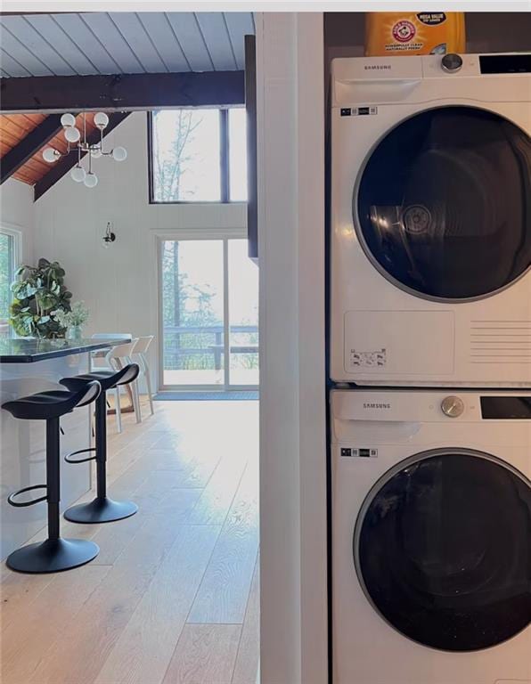 clothes washing area featuring stacked washer and clothes dryer, wood ceiling, and wood-type flooring