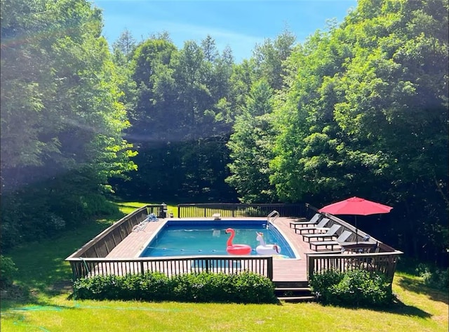 view of swimming pool featuring a lawn and a wooden deck