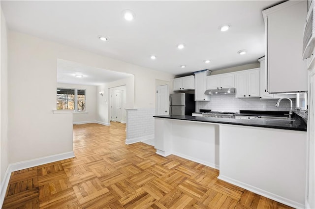 kitchen with stainless steel fridge, tasteful backsplash, light parquet floors, sink, and white cabinetry