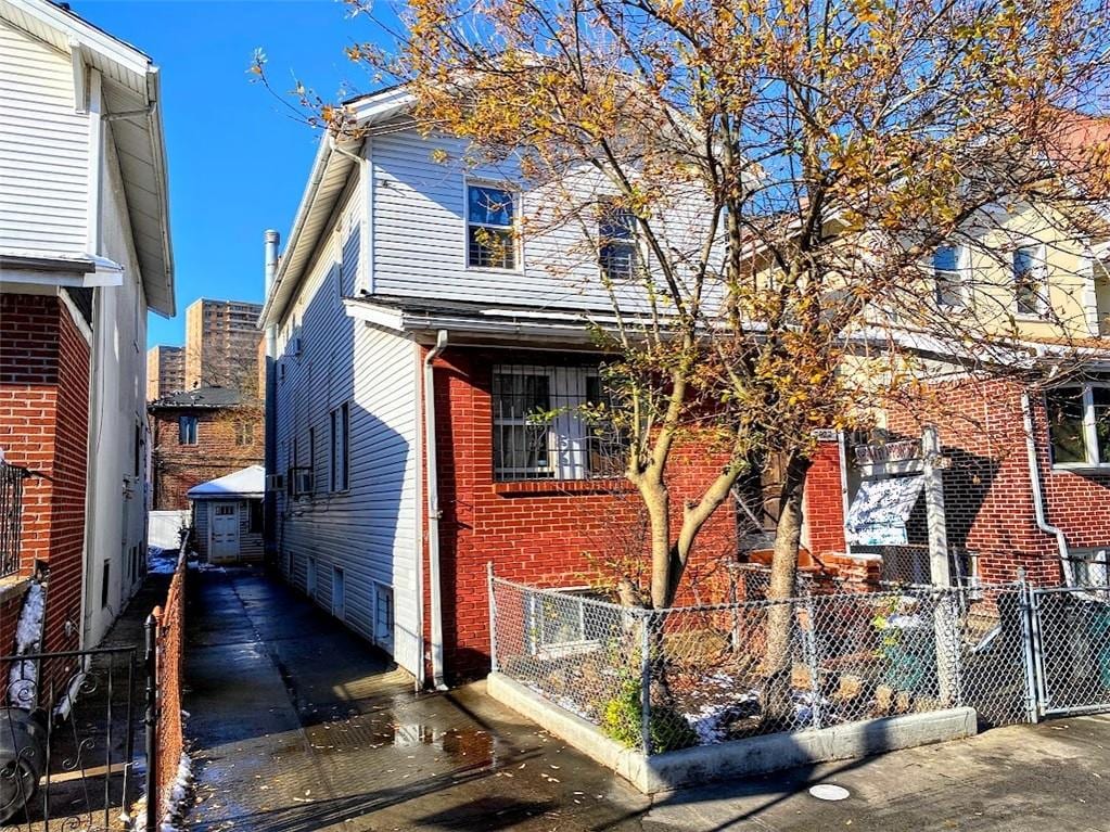 view of front of home featuring fence and brick siding