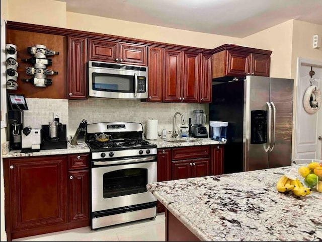 kitchen featuring stainless steel appliances, light stone counters, and decorative backsplash