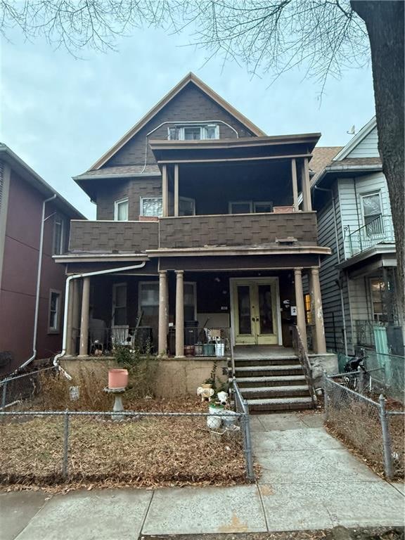 view of front facade featuring a porch, a balcony, and french doors