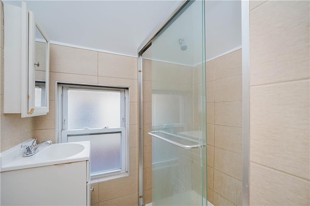 bathroom featuring a stall shower, vanity, and tile walls