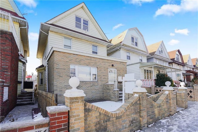 view of front of home with brick siding, a fenced front yard, a gate, and a residential view